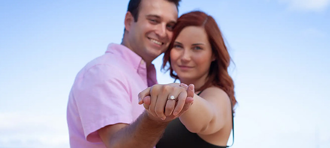 couple embracing on beach, focus on ring on outstretched hand